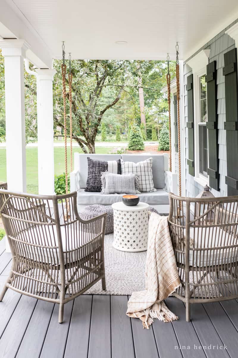 Coastal and beachy front porch with rattan furniture and a porch swing