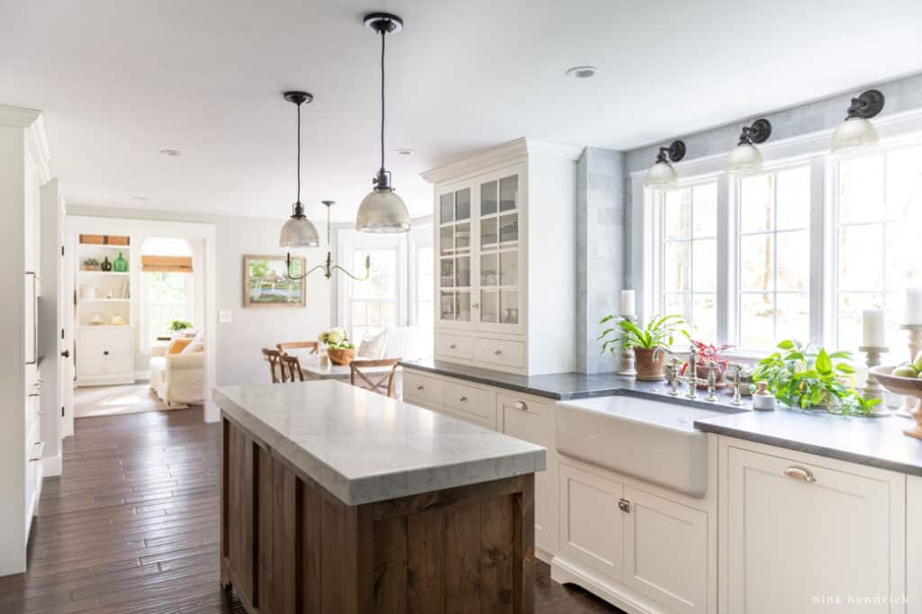 White kitchen with a warm wood island with glass pendants