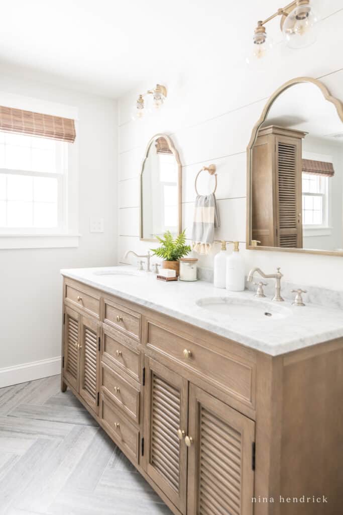 Coastal bathroom with warm wood vanity, marble, shiplap, and warm accents