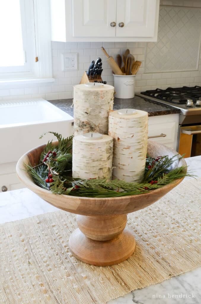 Wooden pedestal bowl with DIY birch candleholders and fresh green clippings