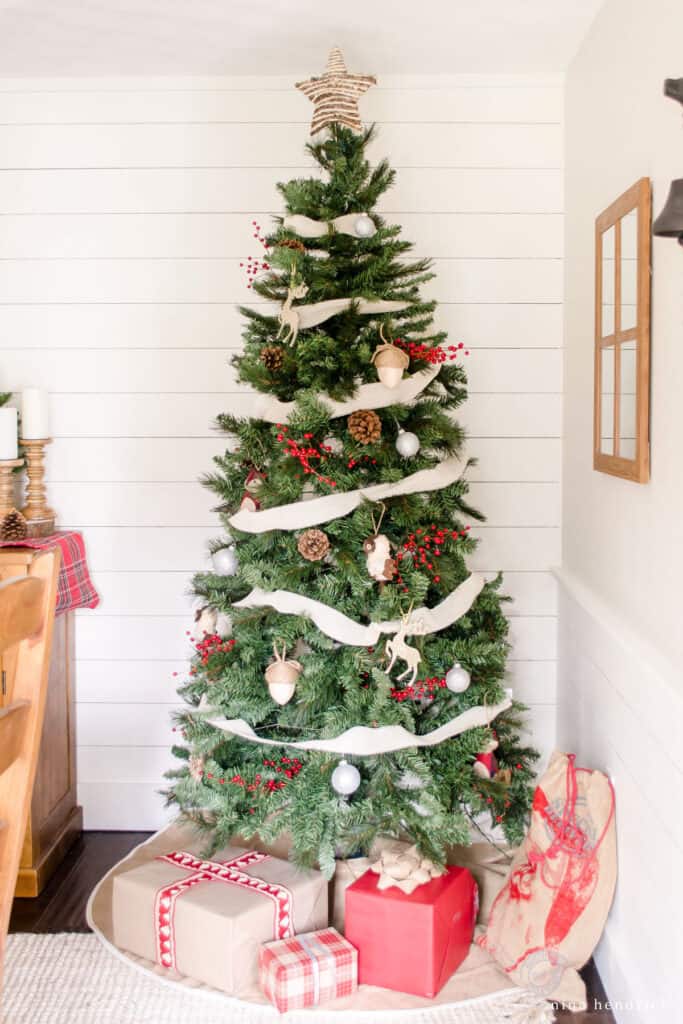 Christmas tree decorated with cozy woodland stuffed animals and berry springs with presents below. 