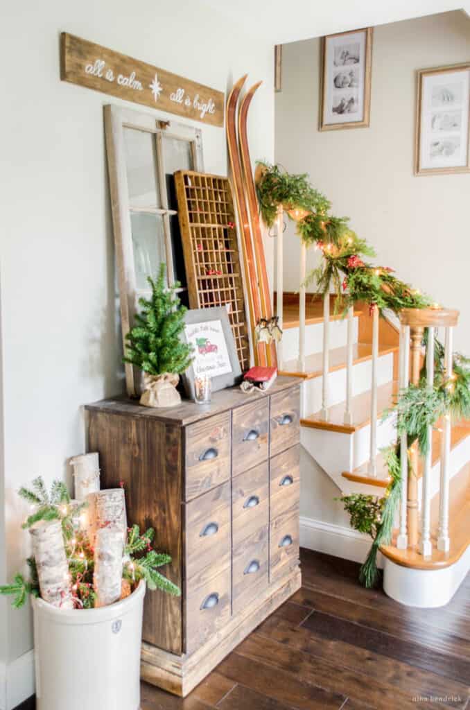 Warm and cozy Christmas decorating ideas for the foyer — vignette with card catalog and birch log arrangement with vintage skis.