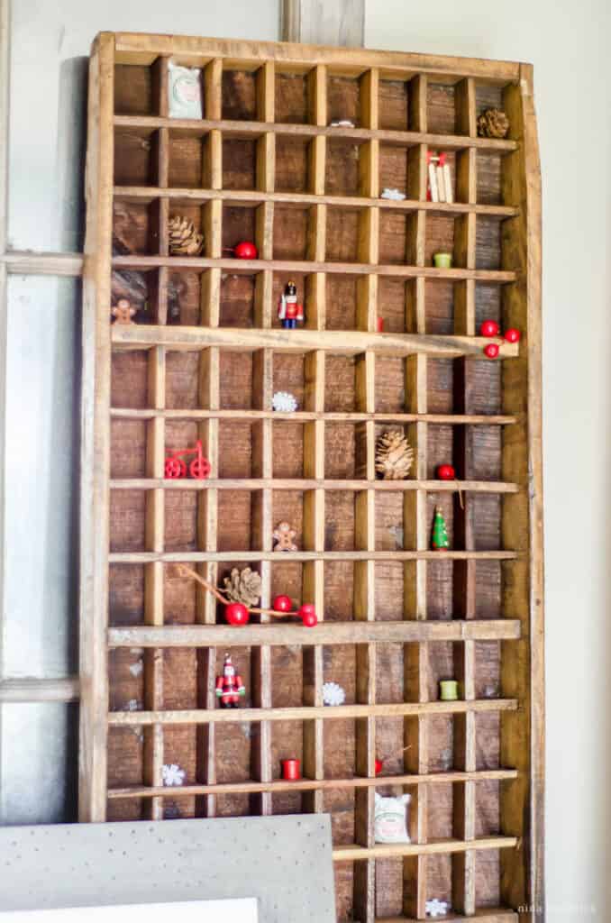 Vintage wooden printer's tray with miniature Christmas decor ornaments and wooden beads.