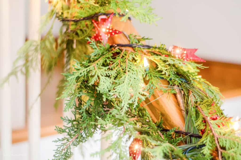 Fresh garland and Christmas lights on a stair bannister