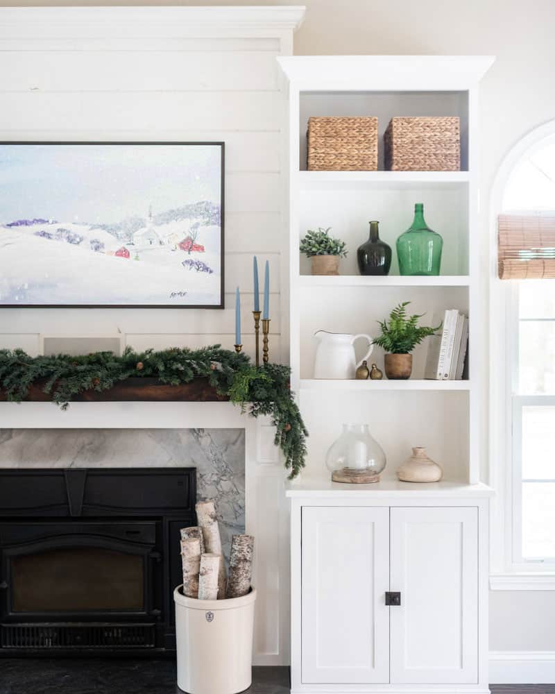 Winter decor around the fireplace mantel with green and blue accents