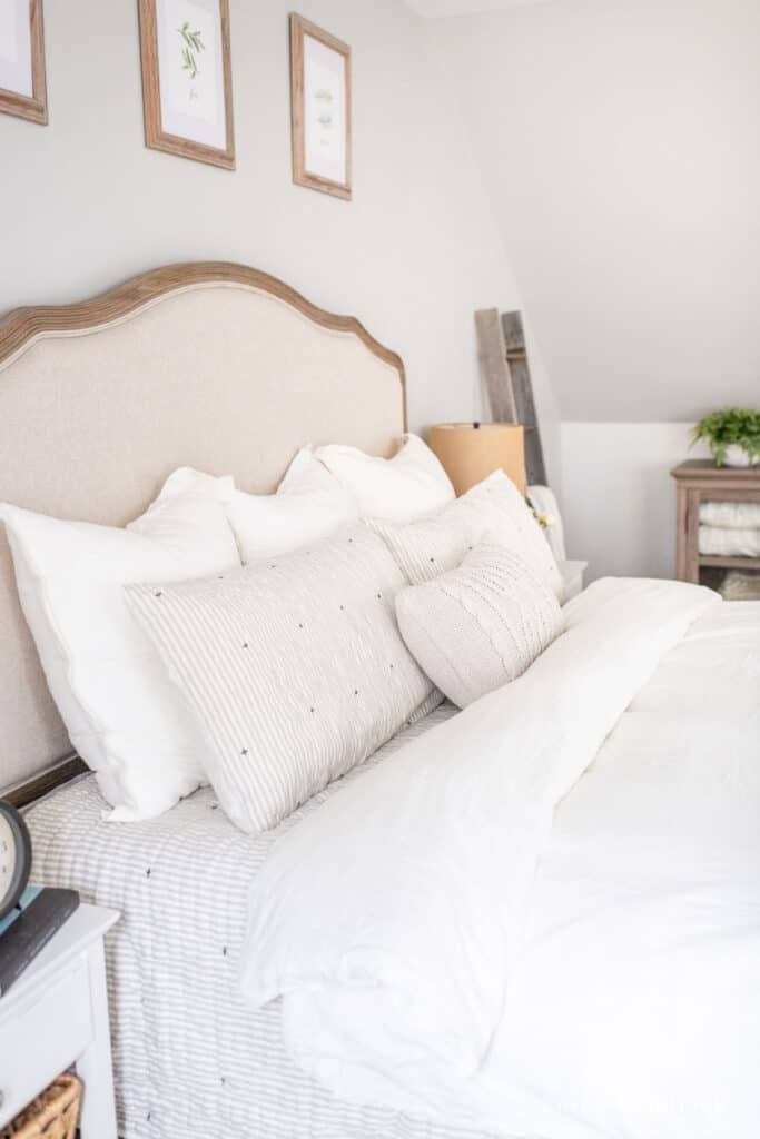 Bed with white and gray bedding and a linen headboard
