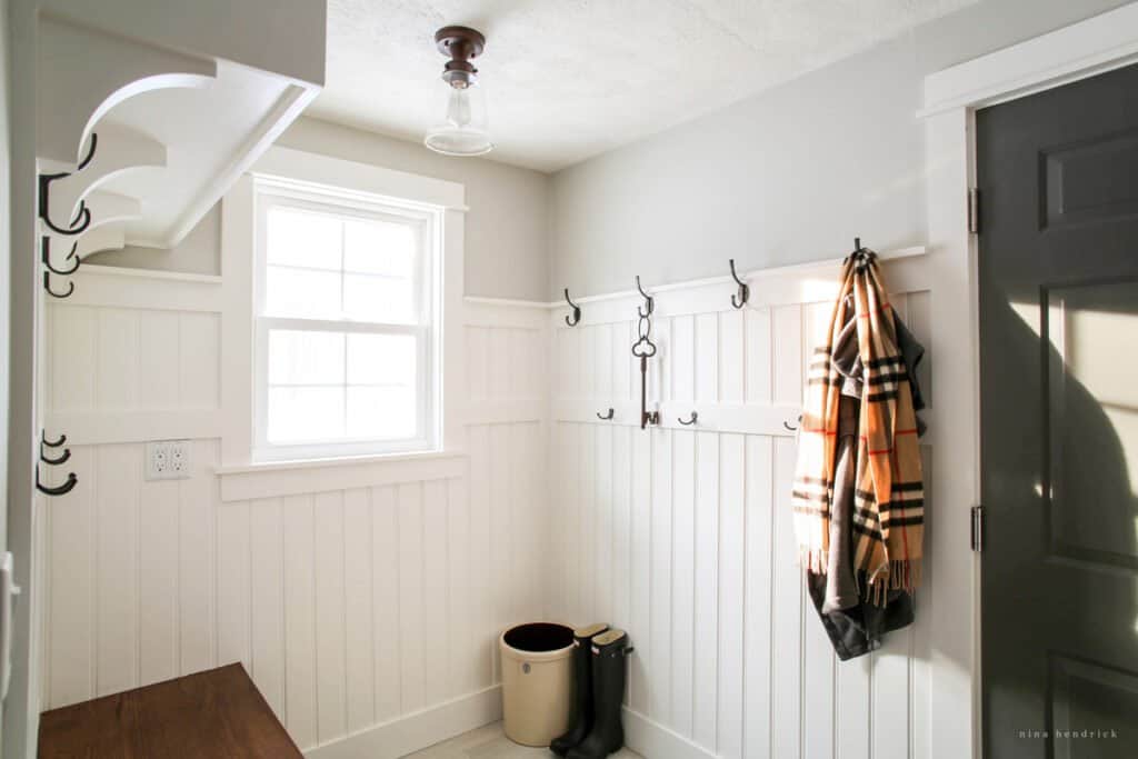 Sunny coat room with white beadboard and hooks