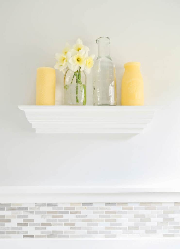 Shelf with yellow candles and daffodils