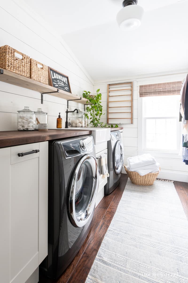 laundry room with white shiplap walls and dark wood accents