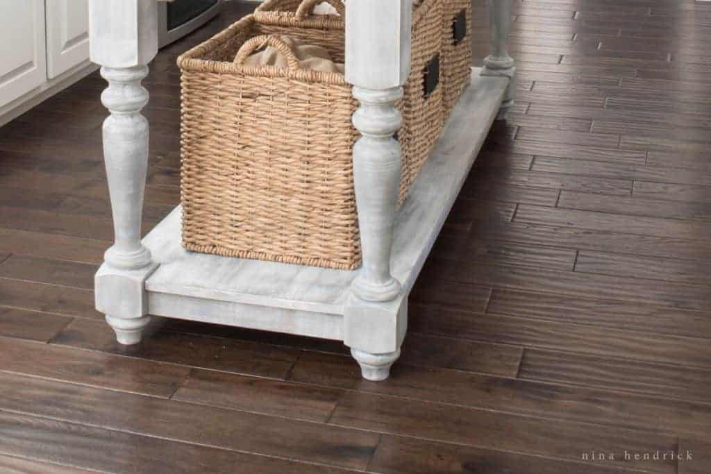 Close up of dark floors with a rustic kitchen island and wicker baskets.