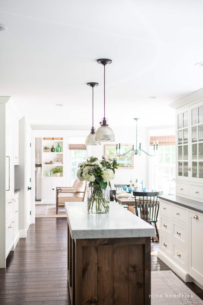 Kitchen with white cabinetry and a wood island with marble countertop.