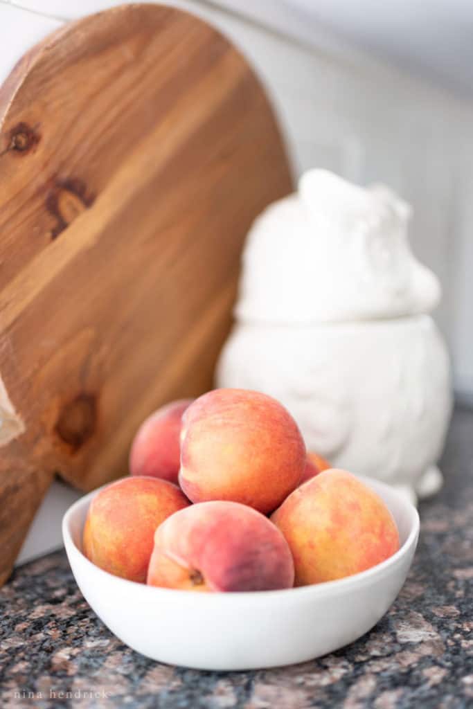 white bowl of apricots with wood cutting board and owl cookie jar