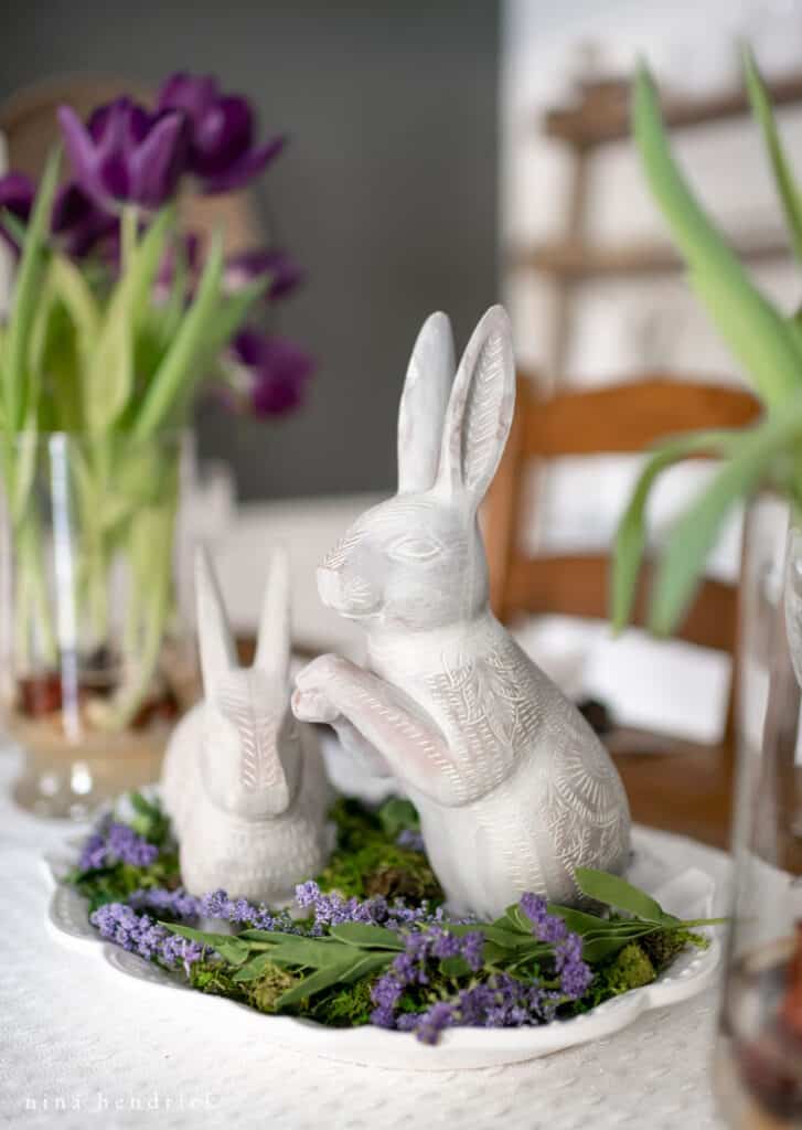 Resin bunny centerpiece on a removable tray with purple flowers.