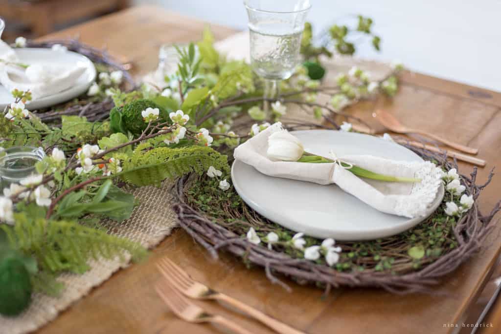 Easter table setting with ferns, twigs, and a white tulip.