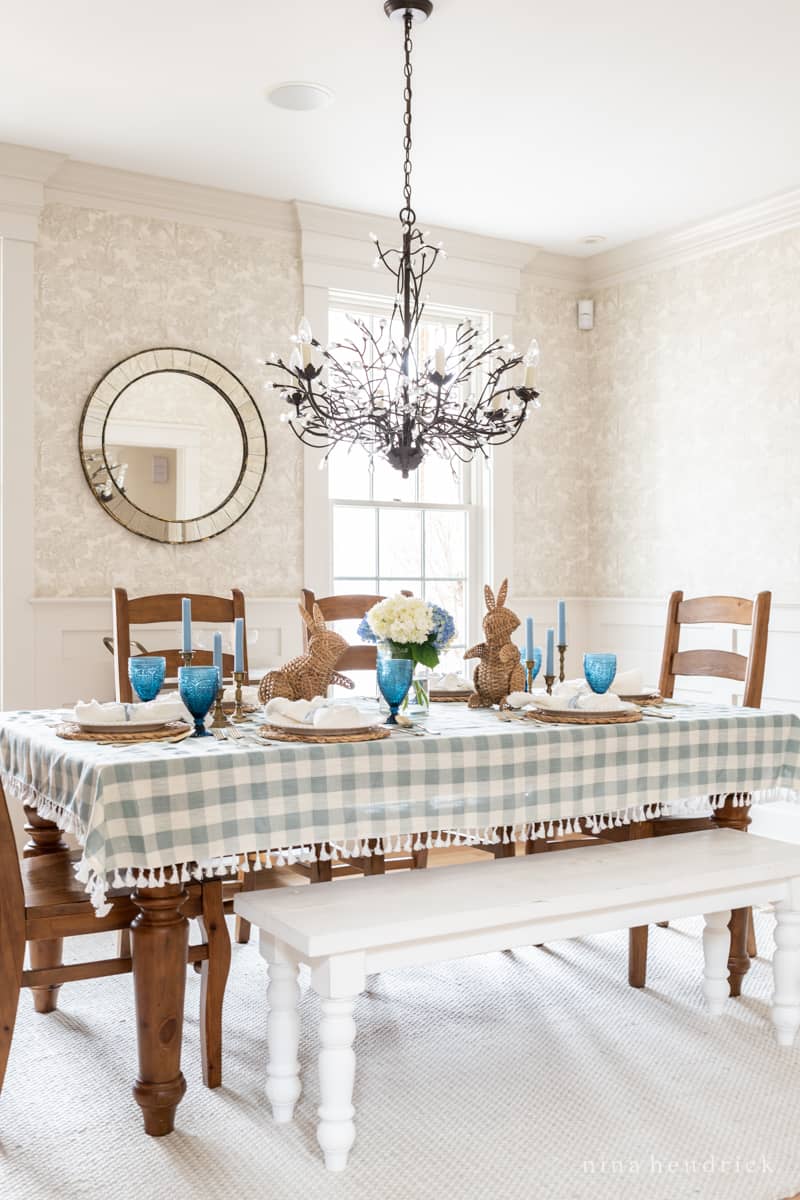 Easter tablescape with blue gingham tablecloth and wicker bunnies.