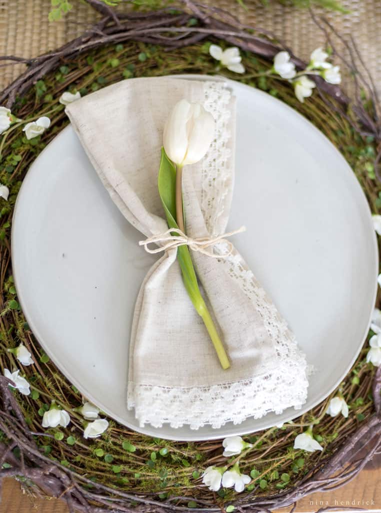 Place setting with twig charger and napkin with tulip.