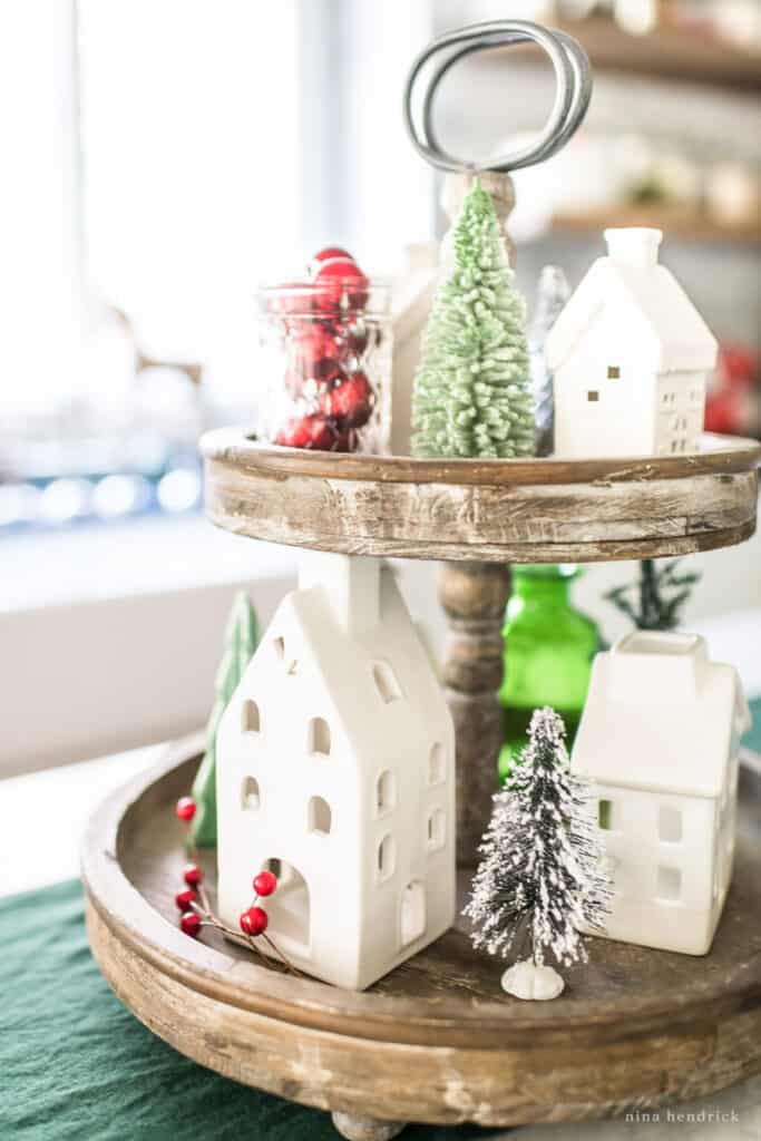 Tiered wooden tray with Christmas village and green accents