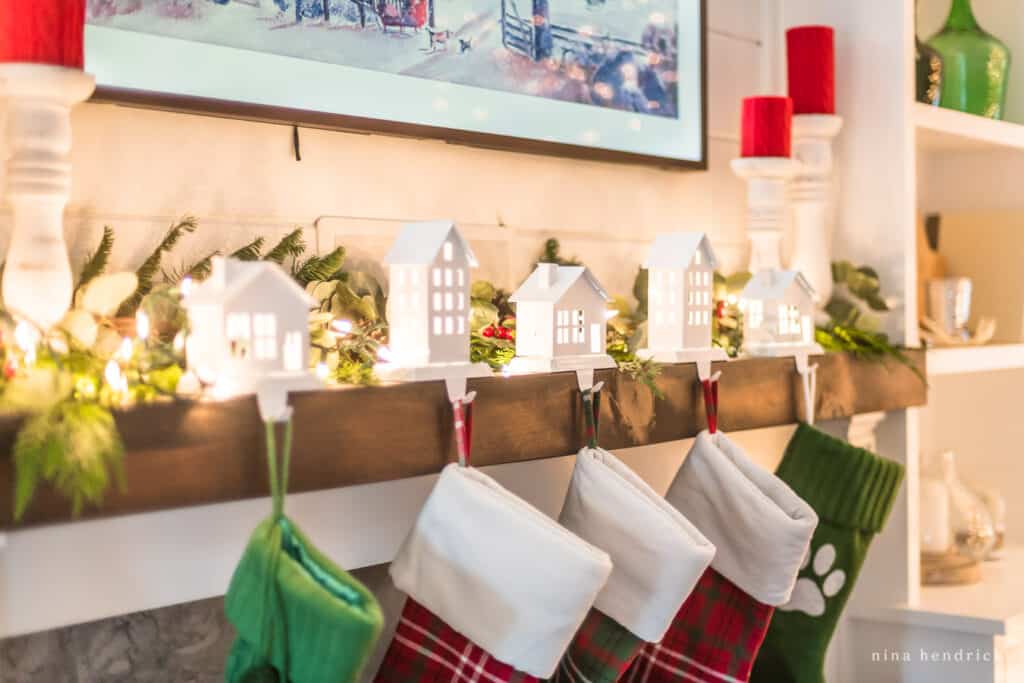 Christmas mantel with a greenery and stocking hangers shaped like houses