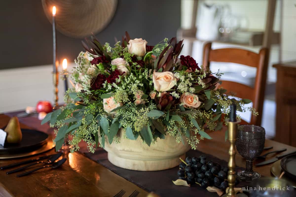An elegant arrangement of fall flowers in a wooden bowl on a table.