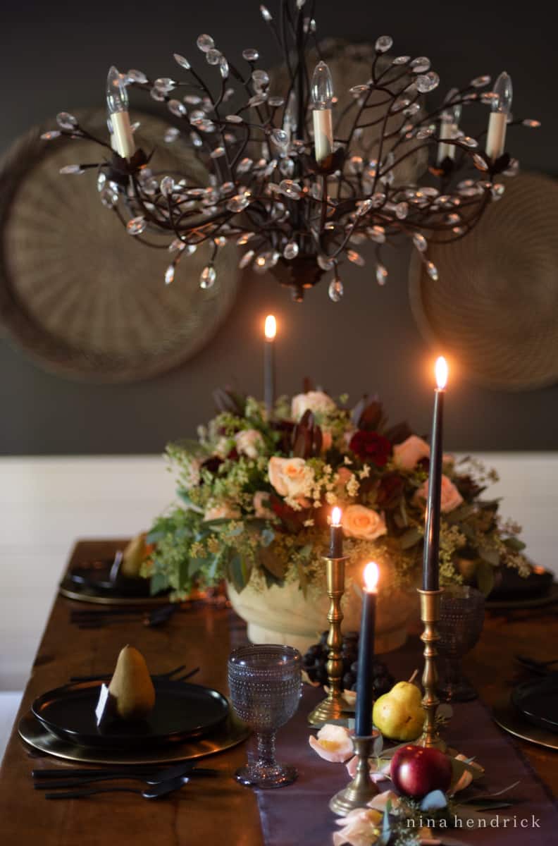 An elegant table setting with candles and a chandelier, creating a stunning fall tablescape.