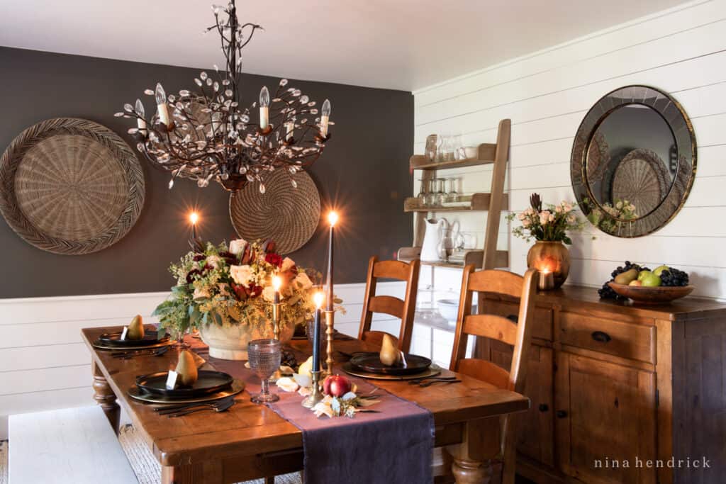 An elegant fall tablescape in a dining room with a table, chairs, and a chandelier.