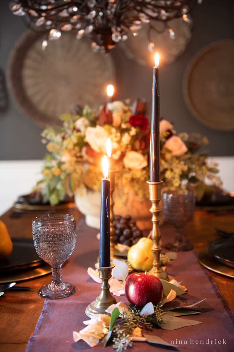 An elegant fall tablescape adorned with candles and fruit.
