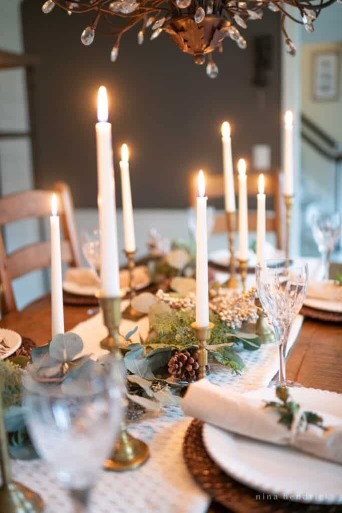 Winter tablescape centerpiece with several white taper candles