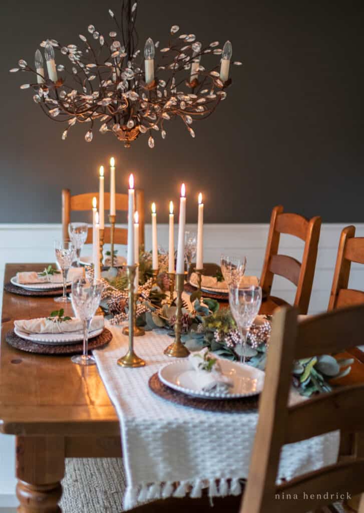 Candlelit winter tablescape with dark wall and crystal chandelier