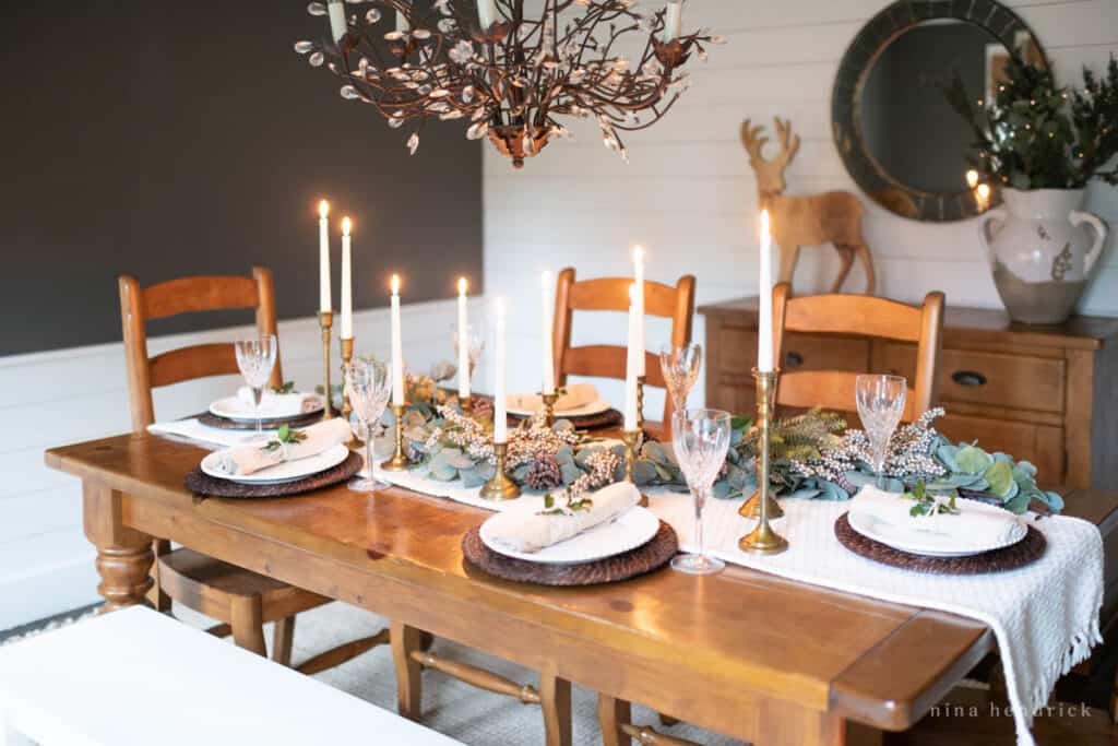 Warm pine table in a dark room with a winter themed table setting