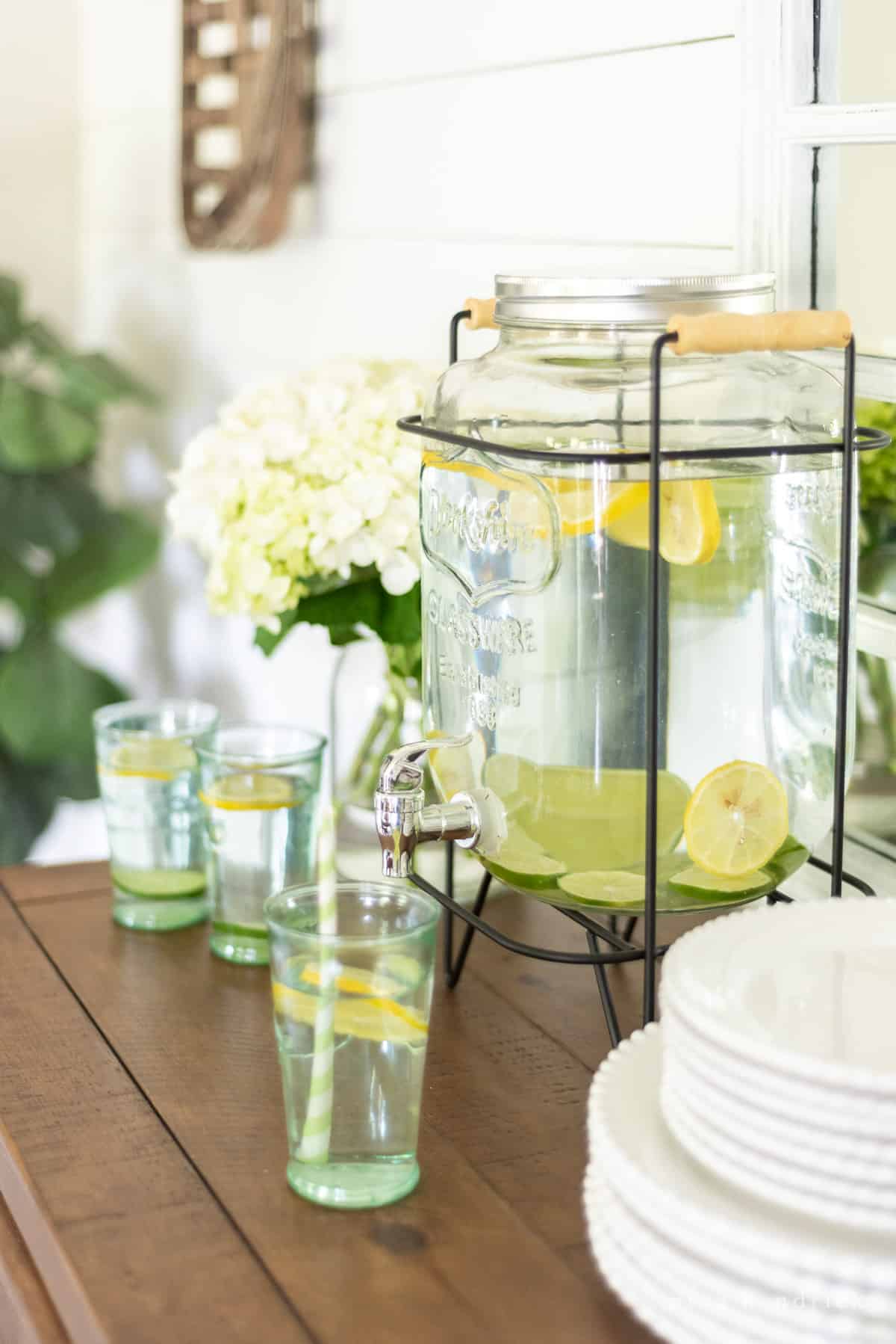 Mason jar drink dispenser with lemons and limes in the water
