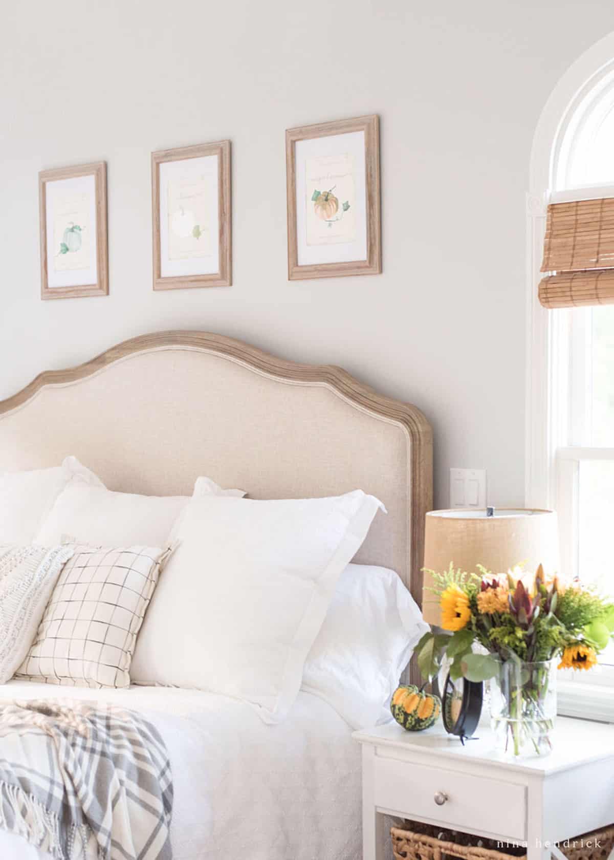 A bedroom with fall decor ideas featuring a white bed and a vase of sunflowers.