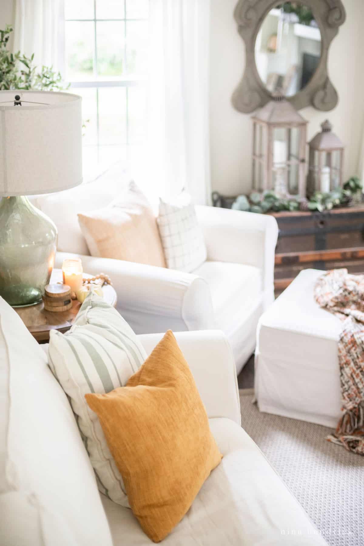 A white living room with orange autumn pillows.