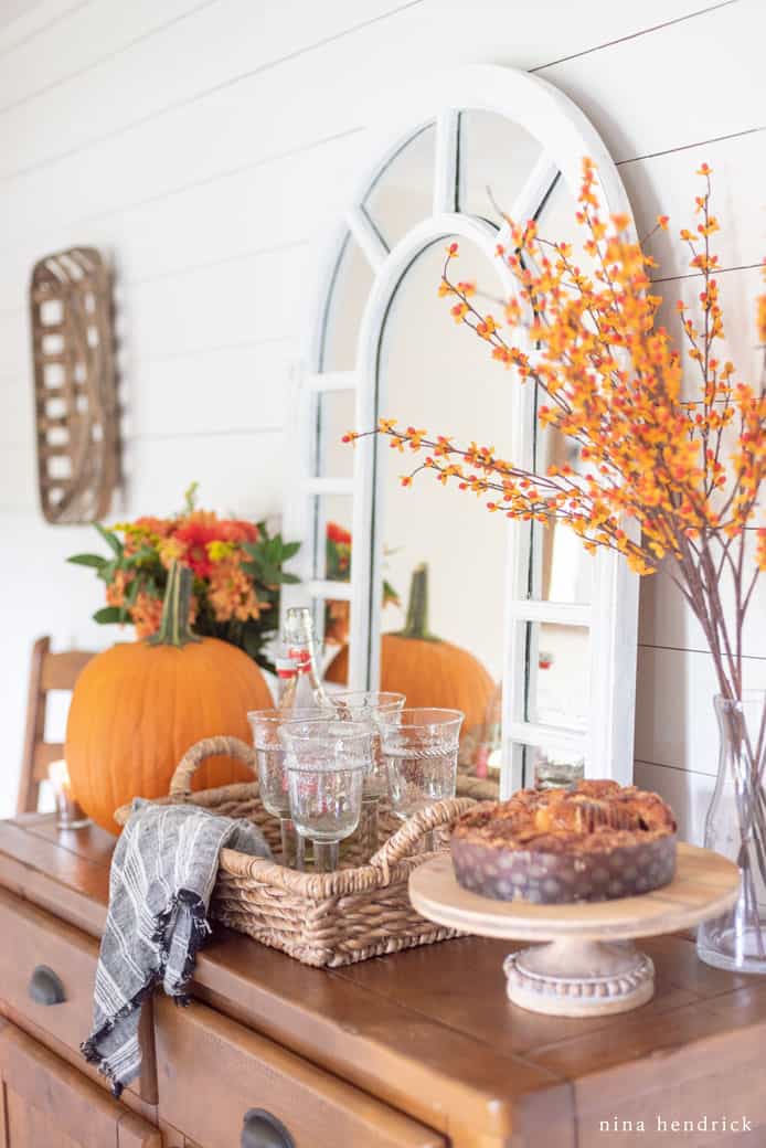 Wood dining room sideboard decorated with an orange pumpkin and flowers for fall decor ideas
