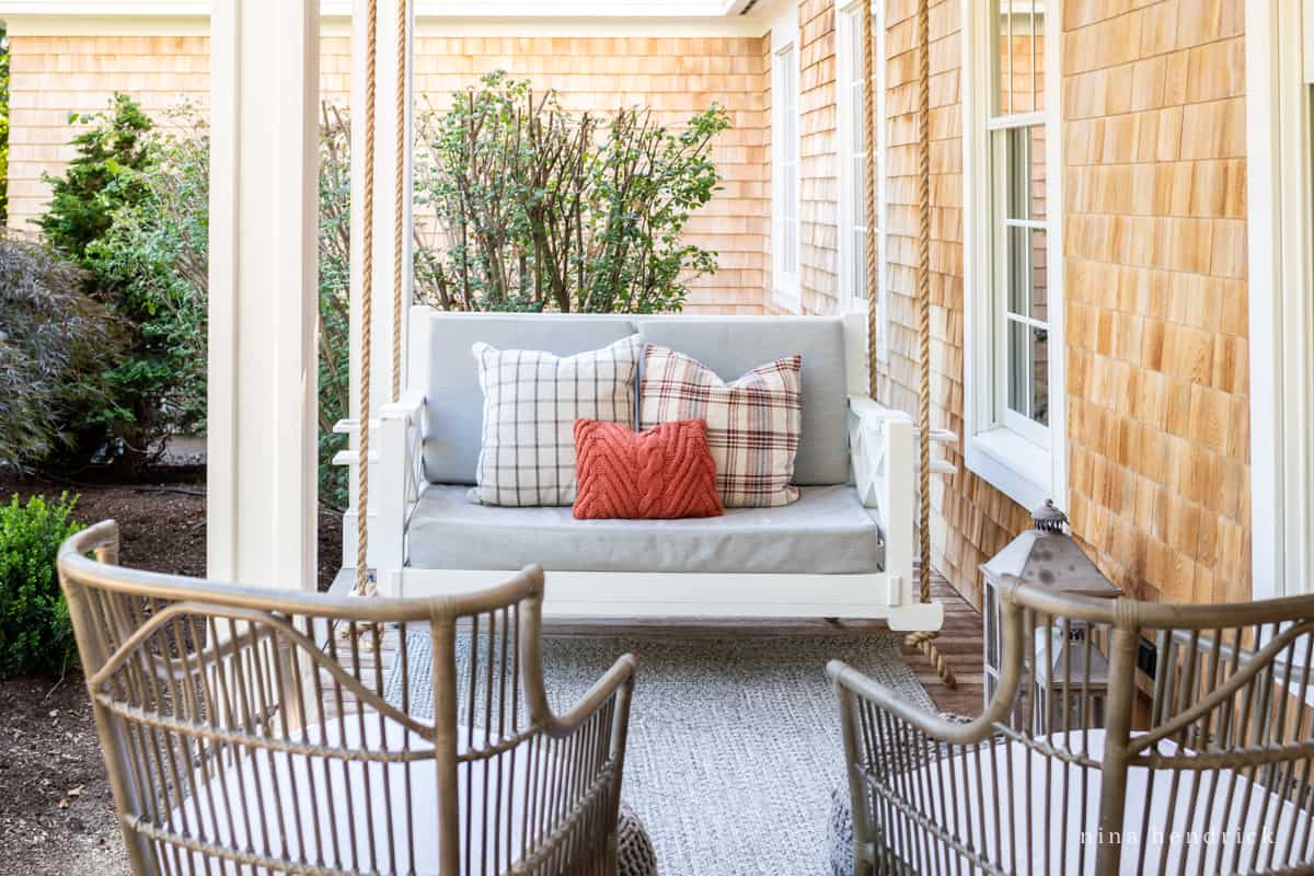 A porch with two wicker chairs and pillows, perfect for fall decor ideas.