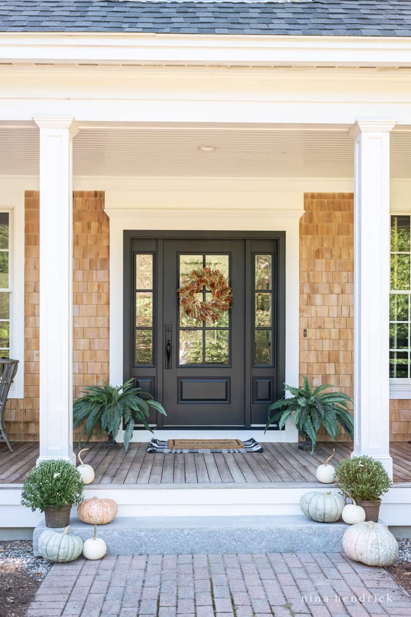 A front porch adorned with pumpkins and a black door.