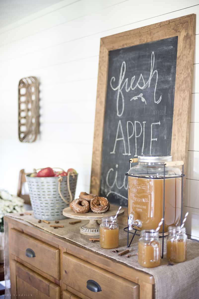 A fall-themed table with a chalkboard and apples on it.