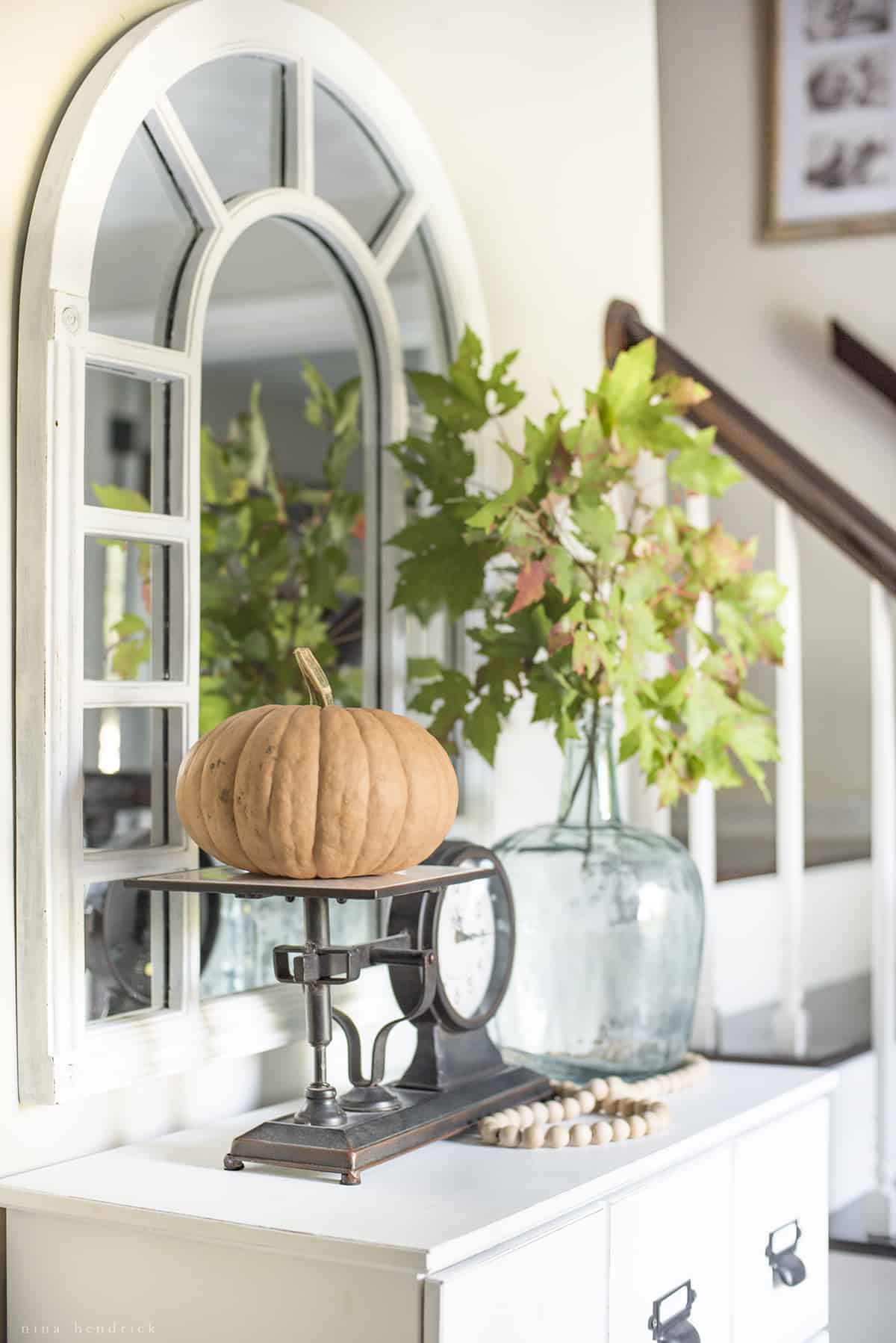 A white dresser adorned with a pumpkin vignette.