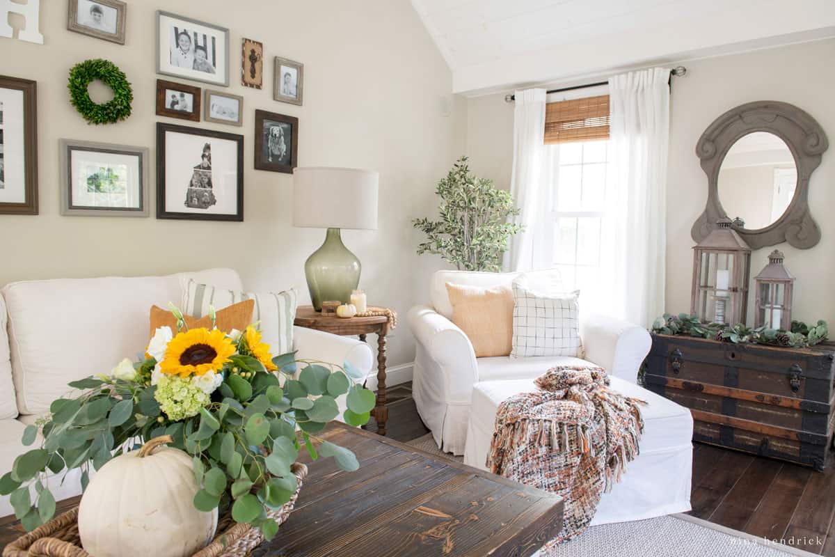 Fall living room adorned with framed pictures and a vase of sunflowers.