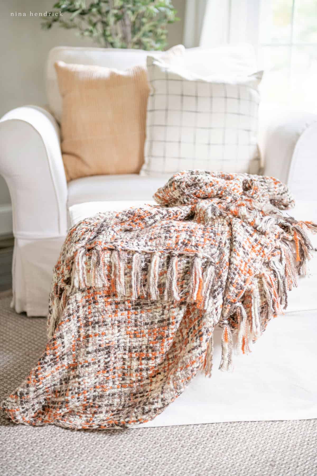 A cozy autumn throw blanket on a white chair.