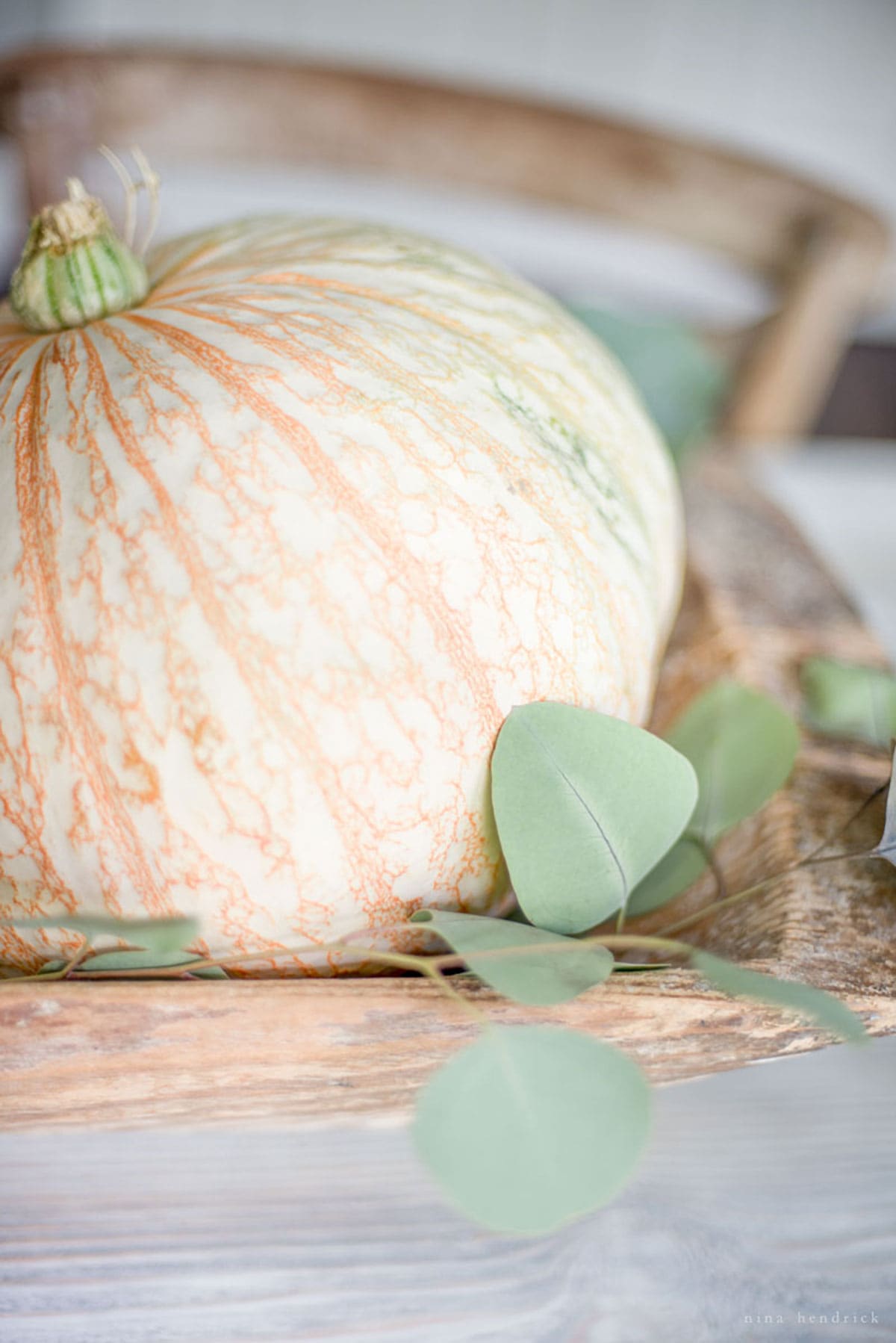 A pumpkin sits on a wooden table during a fall home tour.