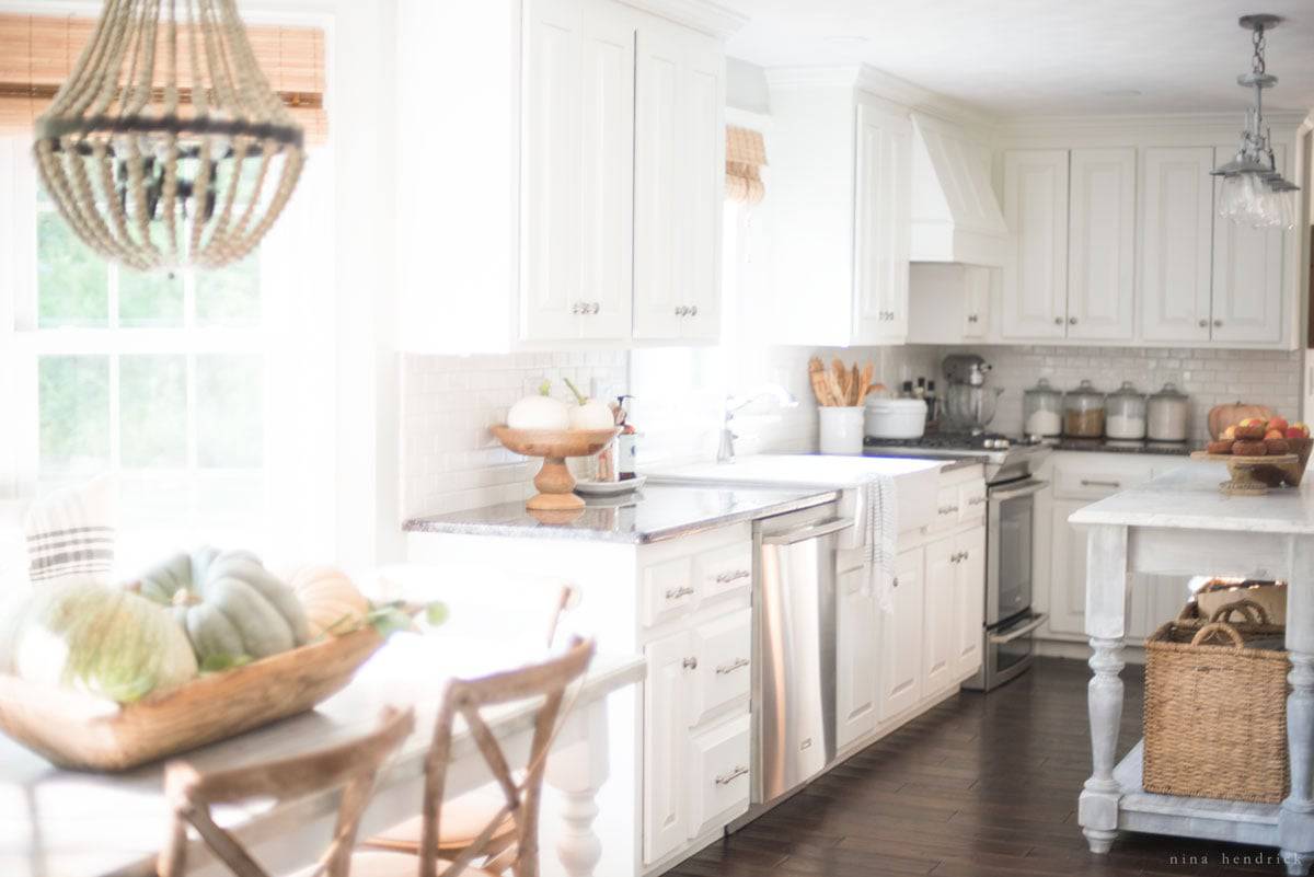 A fall home tour featuring a white kitchen and a table with chairs.