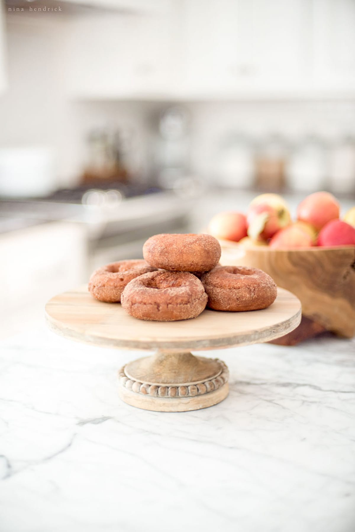 Apple cider donuts on a wooden plate in the kitchen.