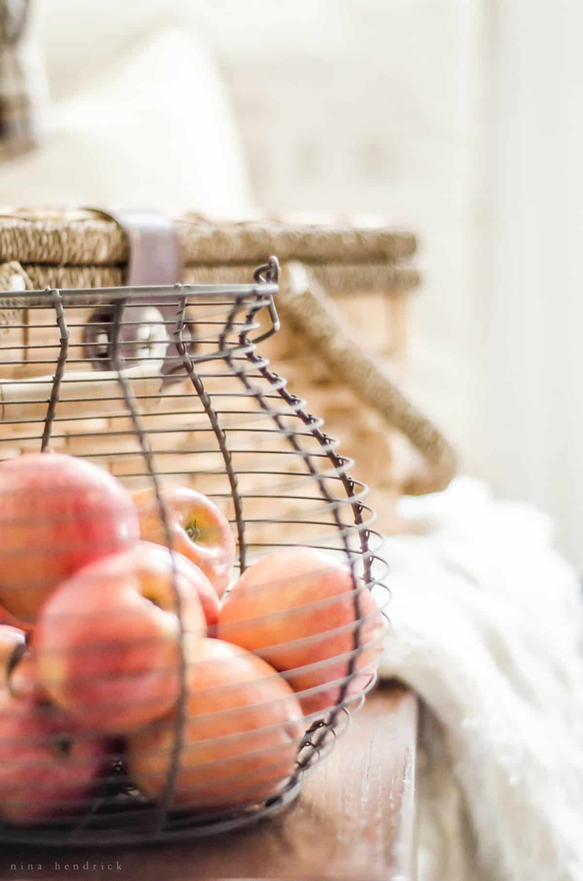 A basket of apples on the mudroom bench.