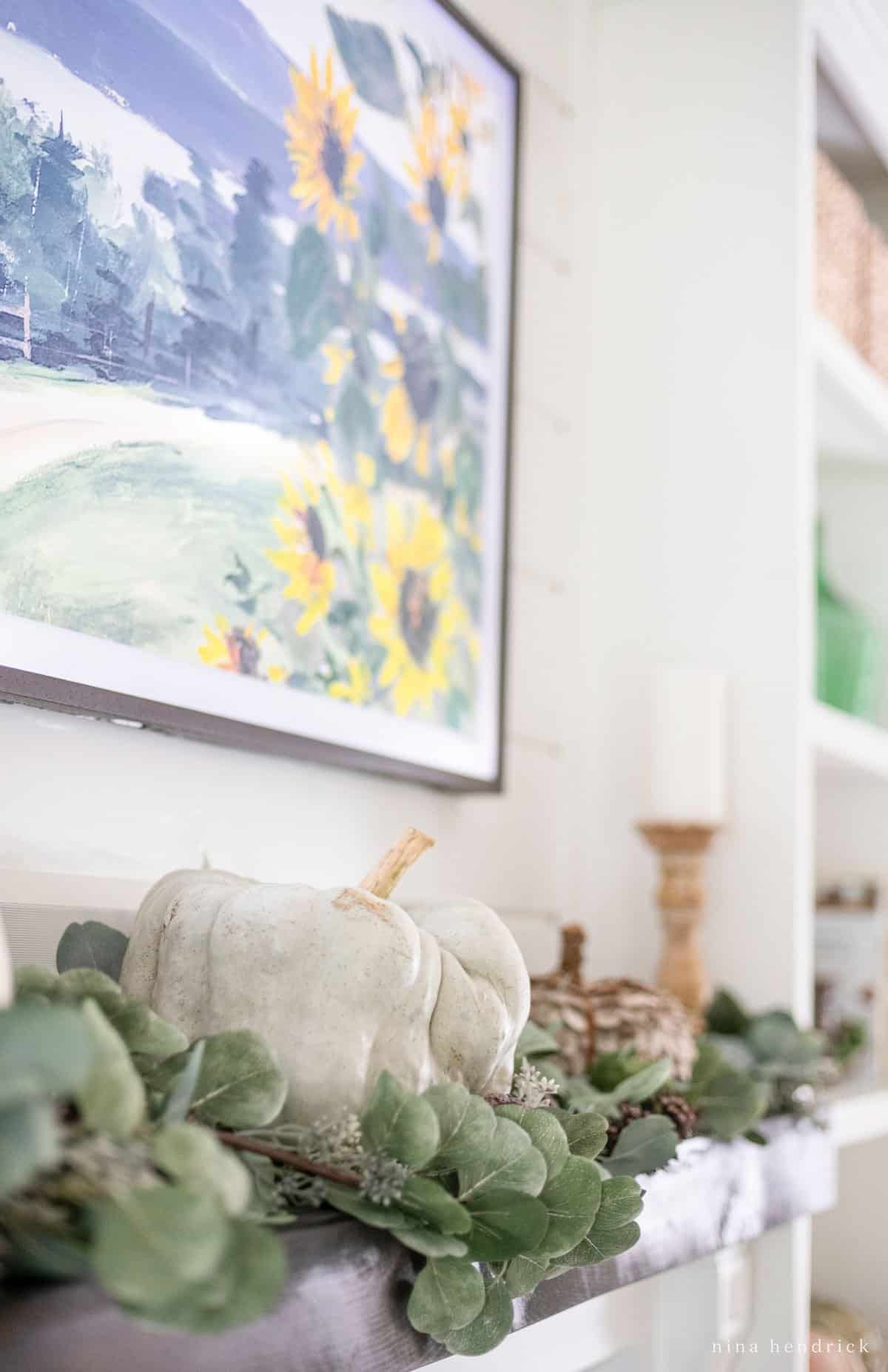 Eucalyptus leaves and pumpkins on a mantel.