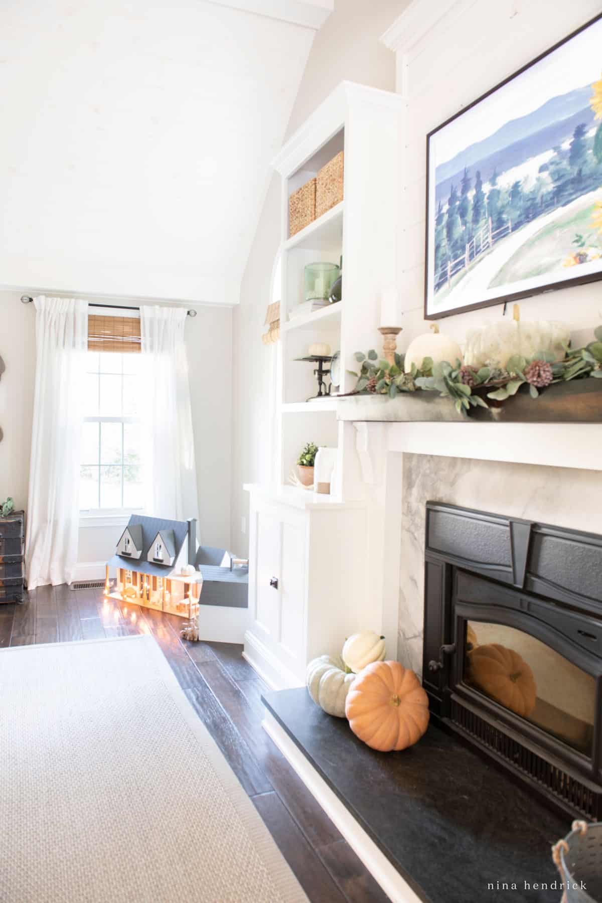 A fall home tour showcasing a cozy living room with a fireplace and pumpkins.