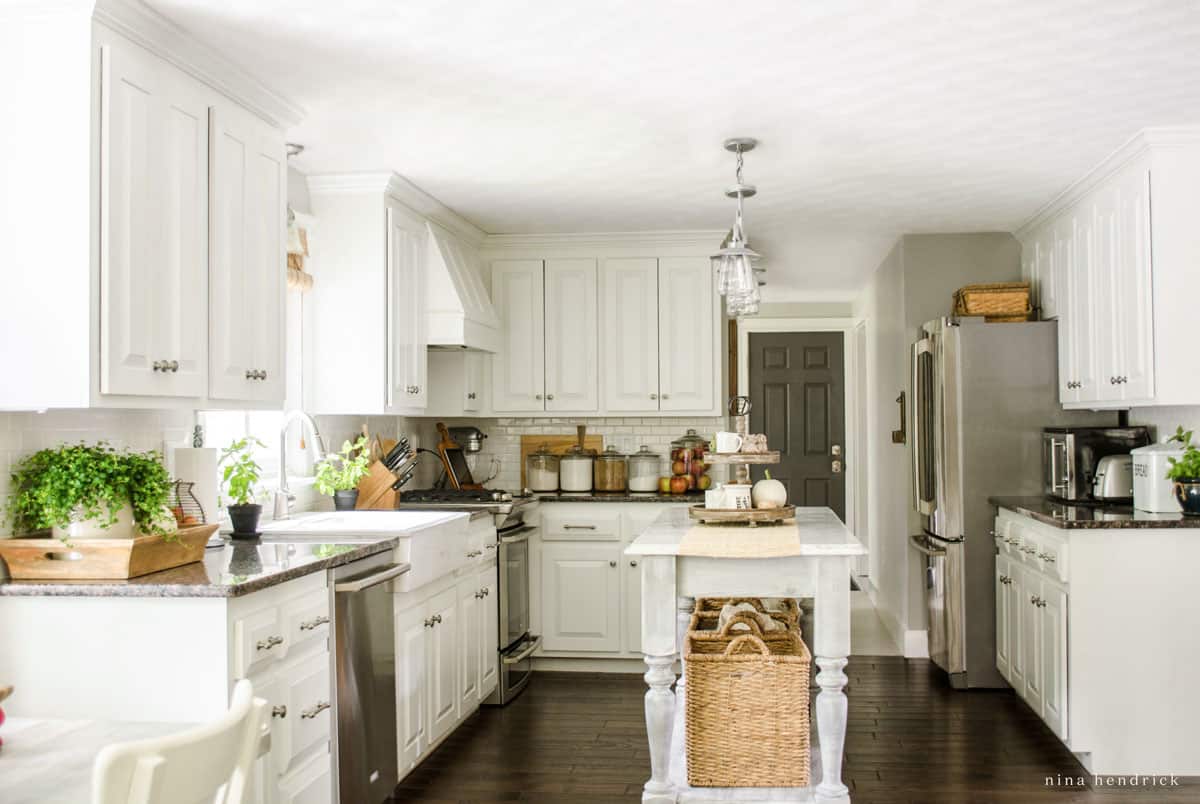 Kitchen with white cabinets and hardwood floors with subtle fall decor.