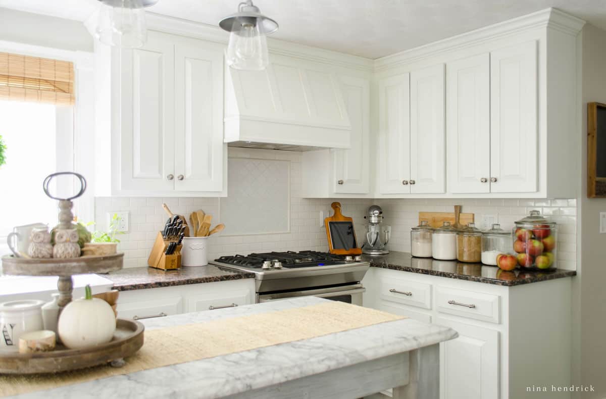 A kitchen decorated for fall with white cabinets and marble counter tops.