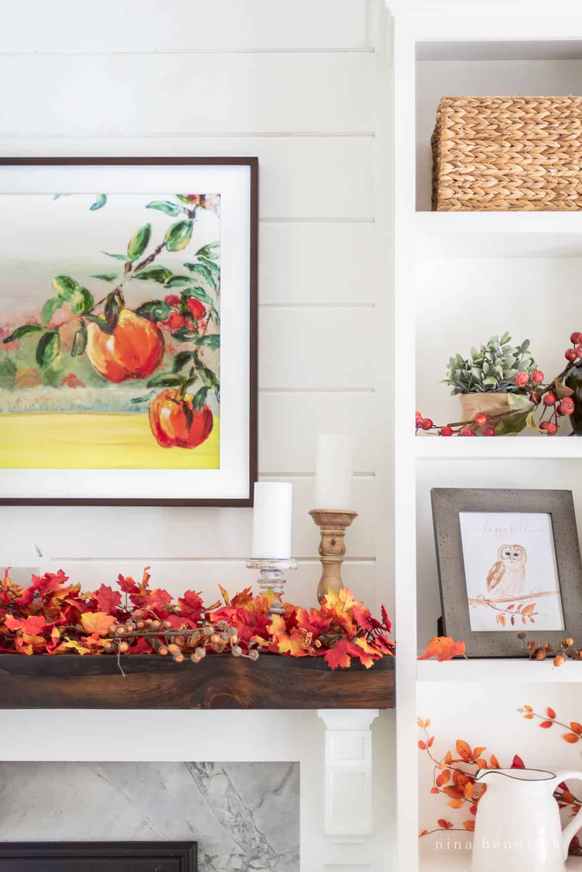 Close-up of a wooden mantel decorated for fall with bright autumn colors and a painting with apples