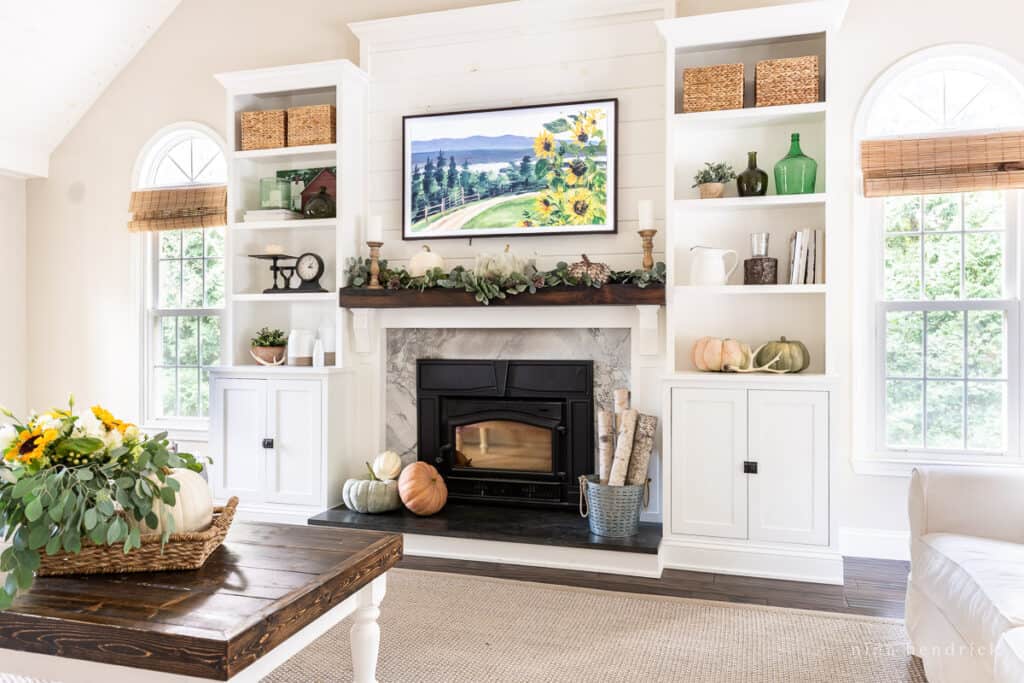 Living room with white fireplace surround decorated for autumn.