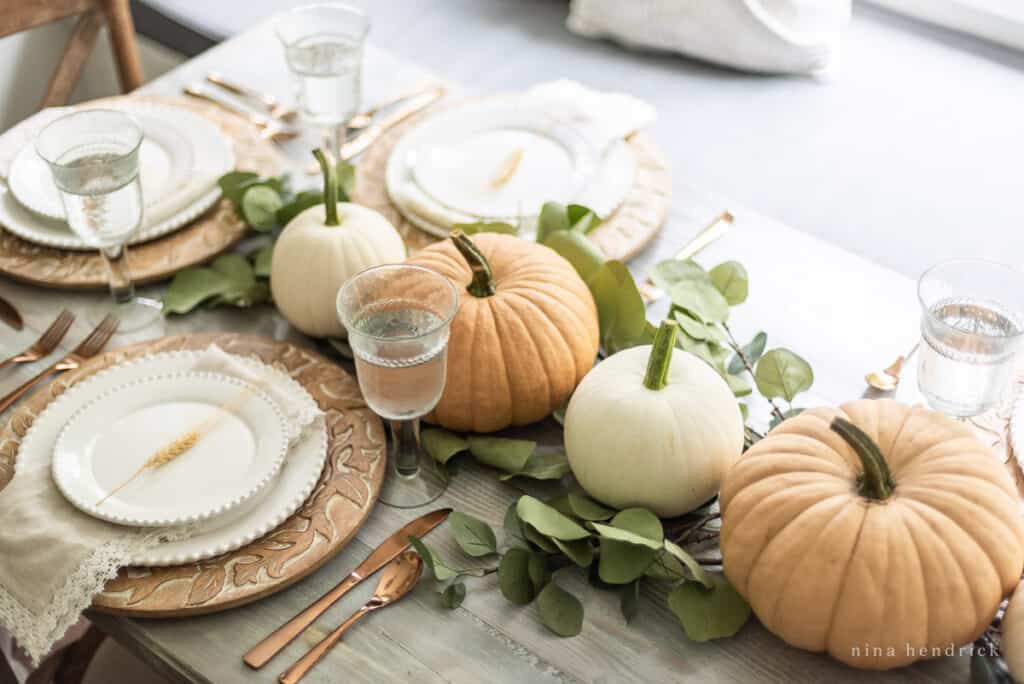 Centerpiece featuring pumpkins and eucalyptus leaves.